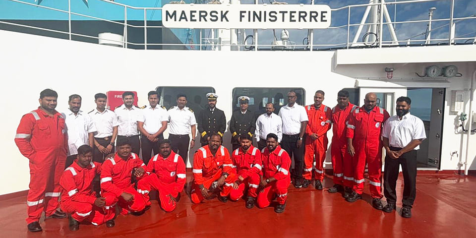 Group photo of the Maersk Finisterre crew in uniform and boiler suits, representing maritime operational readiness and team competence.