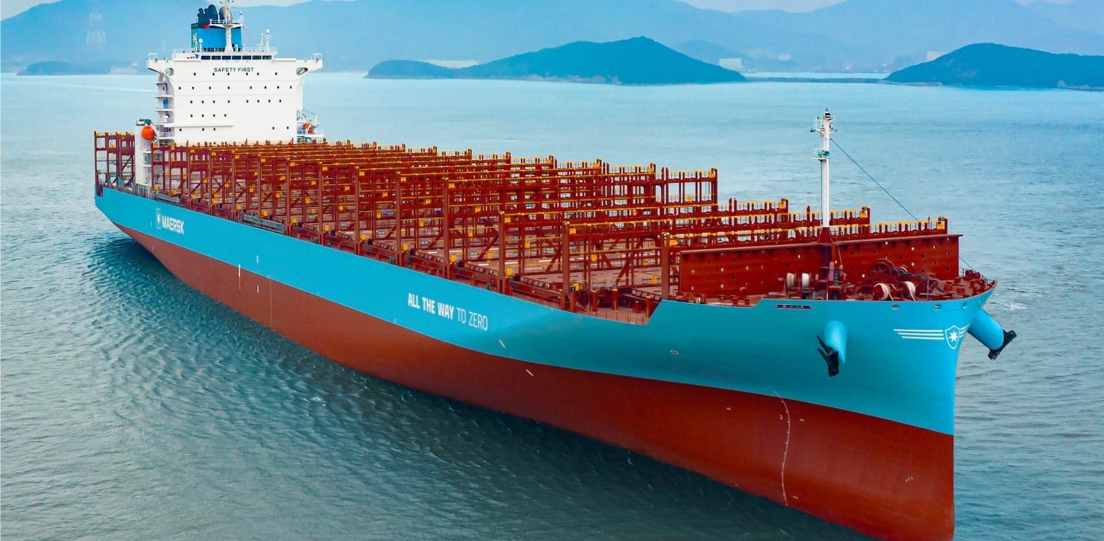 A large Maersk dual-fuel container ship with 'All the Way to Zero' branding sailing at sea, highlighting sustainable maritime decarbonization efforts.