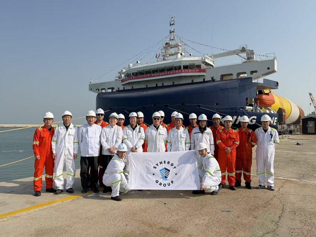 Crew and shore team in safety gear standing before KING ONE with monopiles onboard