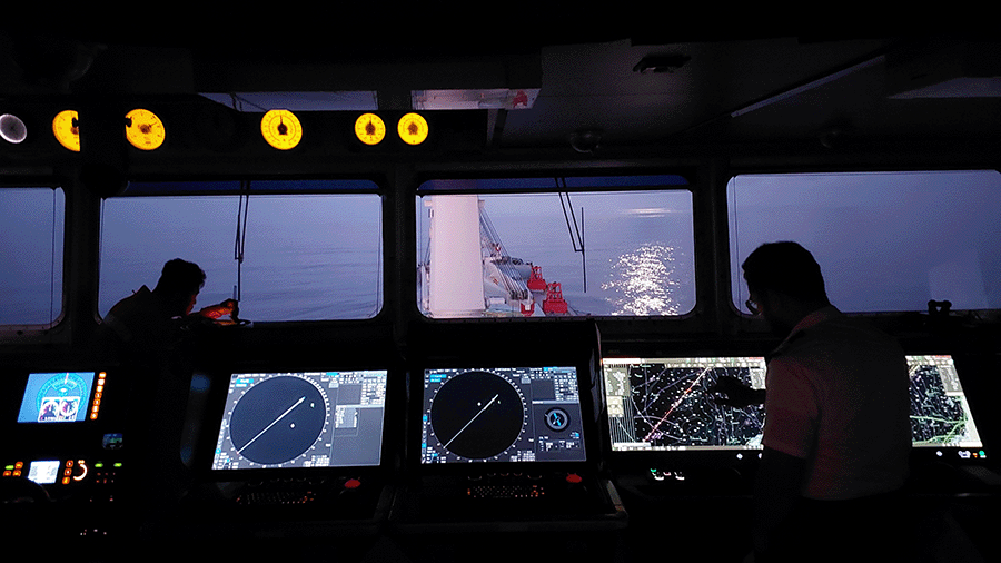 A night watch framed by the glow of bridge instruments, capturing the concentration and vigilance behind safe navigation after dark.